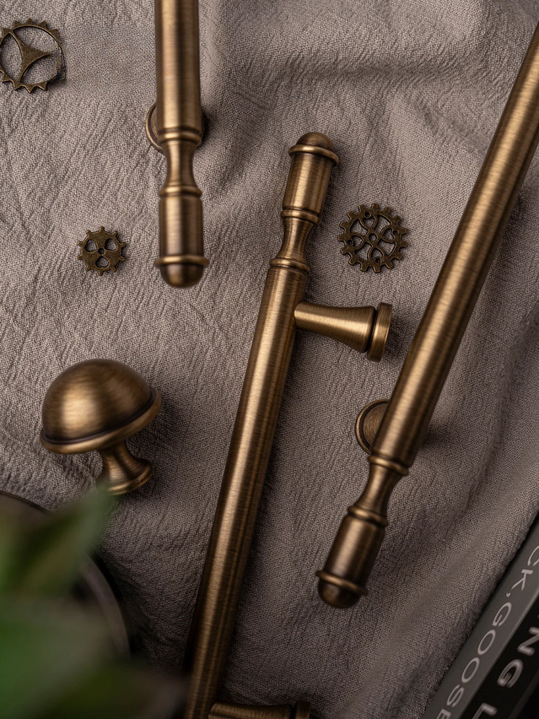 Collection of bronze cabinet handles and knobs on a textured surface.