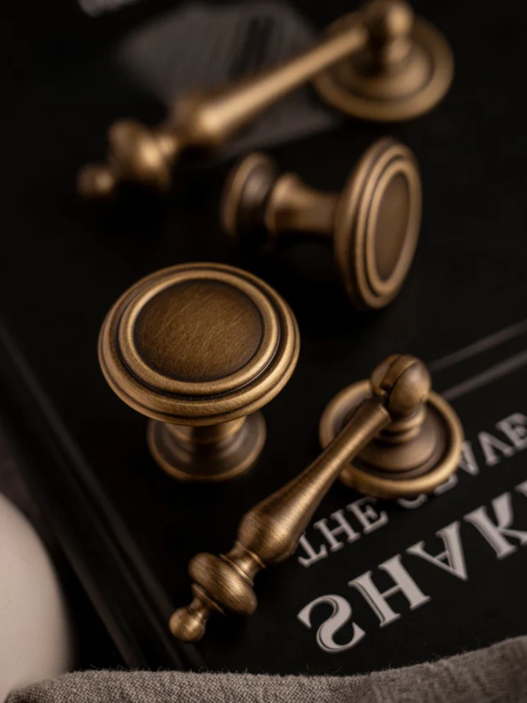 Close-up of bronze cabinet knobs on a dark surface with text.