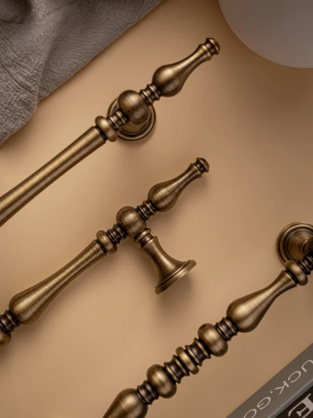 Bronze door handles on a beige surface with a gray cloth in the background