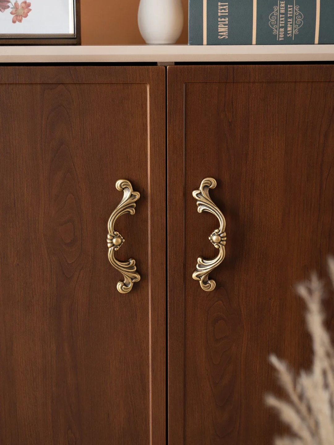 Wooden cabinet with ornate gold handles on a neutral background