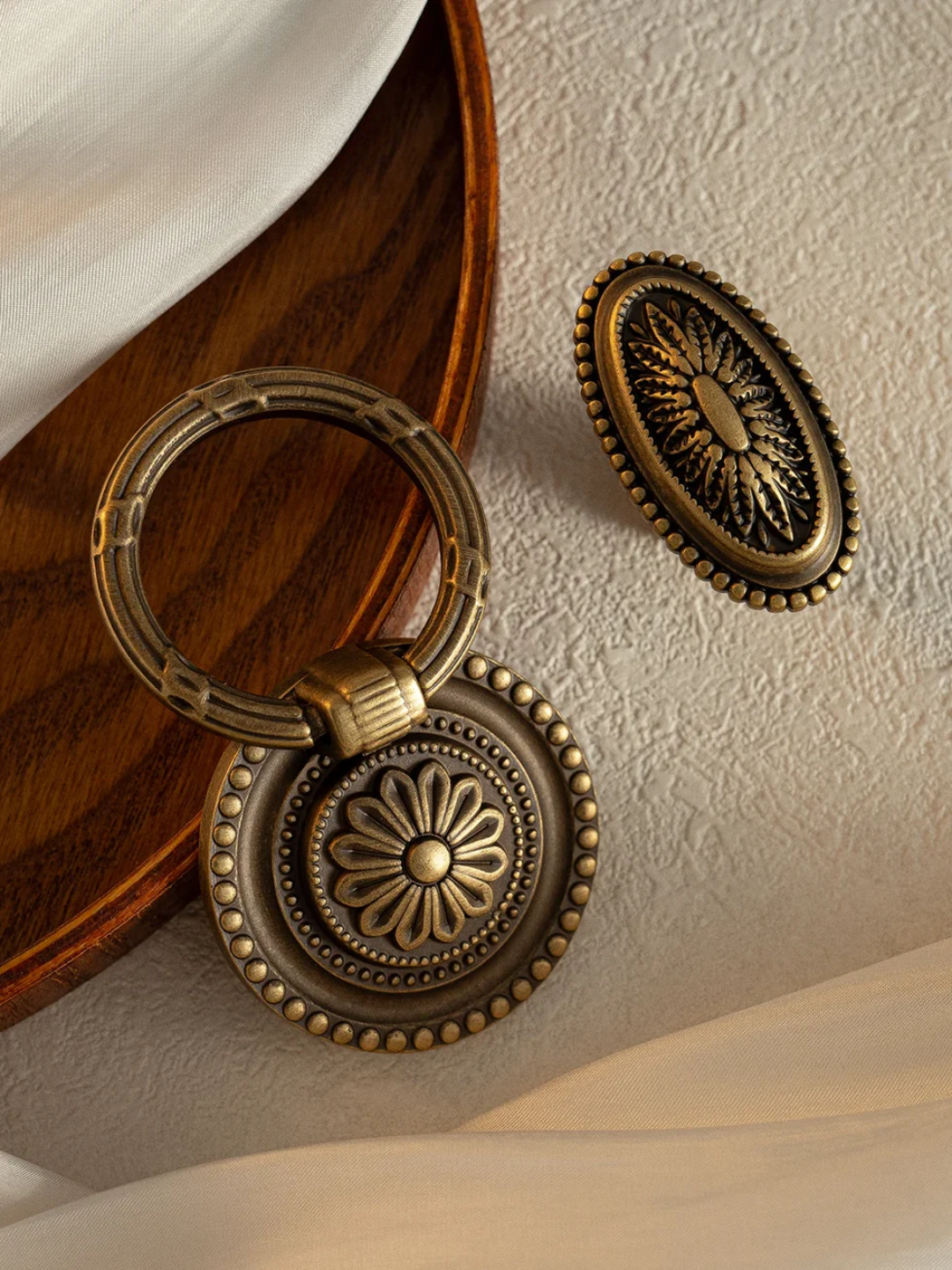 Pair of ornate bronze earrings on a textured surface