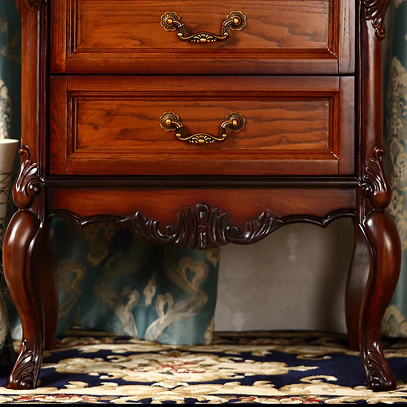 Wooden dresser with intricate carvings and gold handles on a patterned rug.