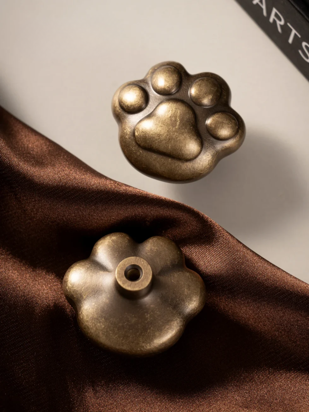 Bronze paw-shaped knobs on a brown fabric background