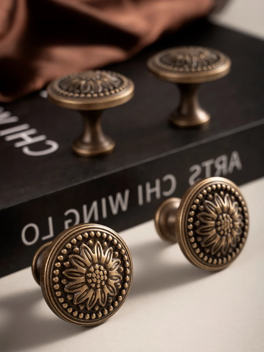 Bronze cabinet knobs with floral design on a book