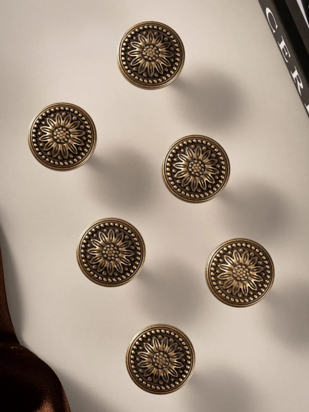 Six brass decorative knobs on a white surface