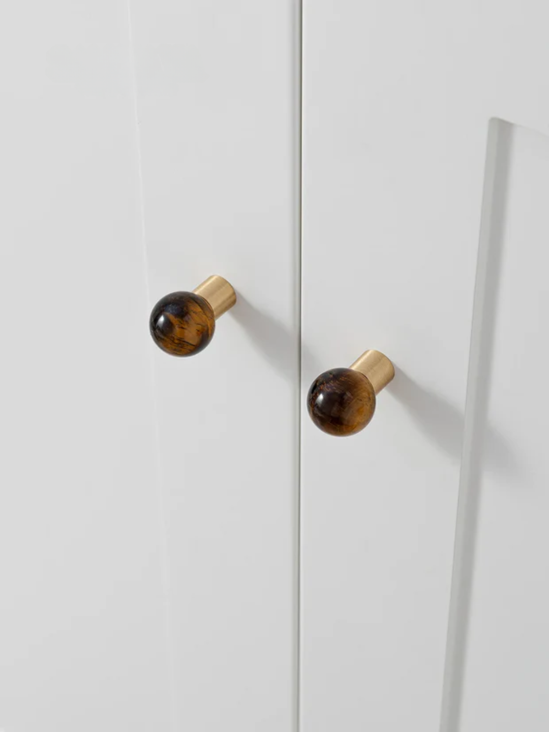 Close-up of a white cabinet with gold and brown knobs.
