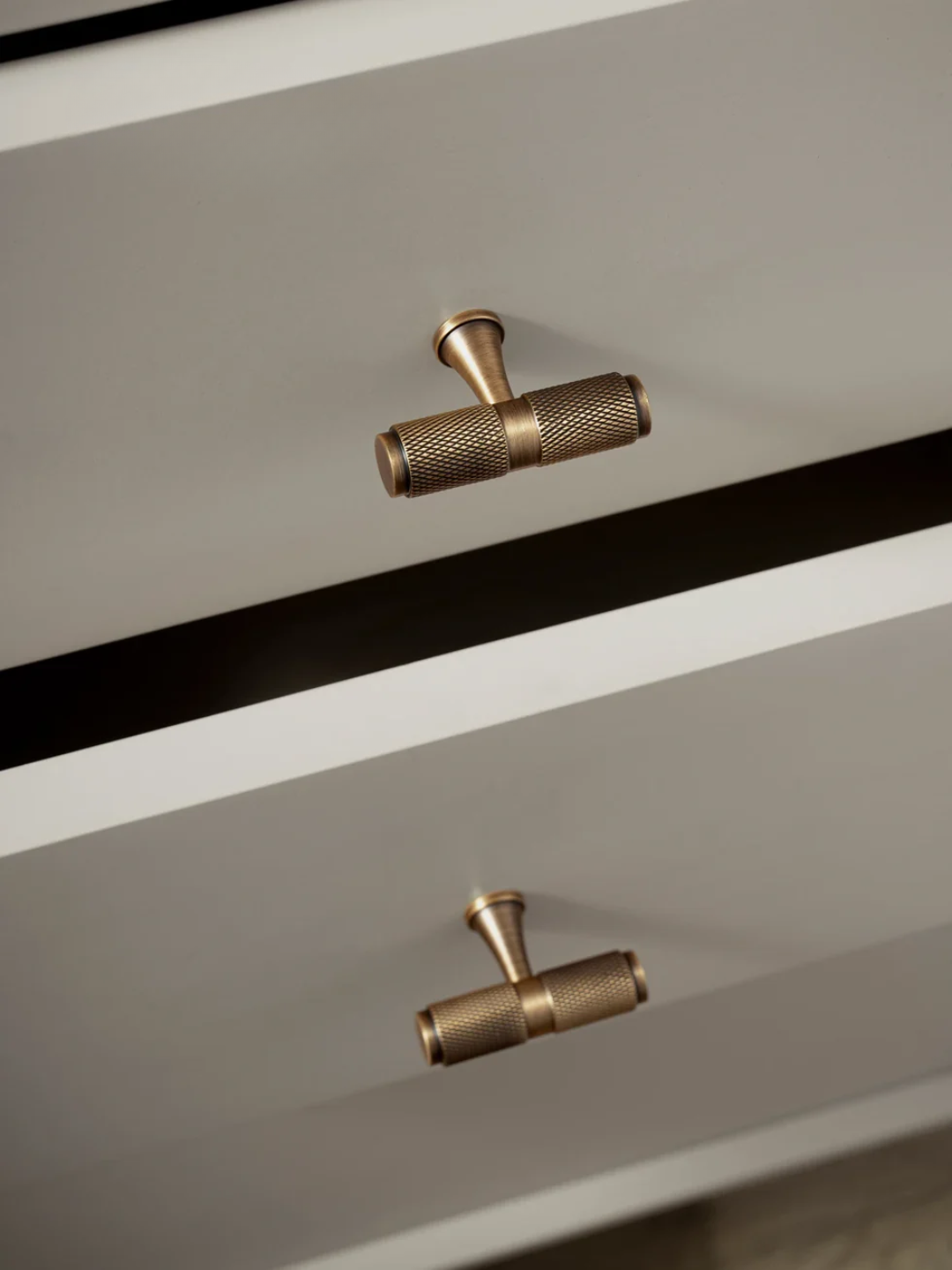 Close-up of a dresser with brass handles on a neutral background