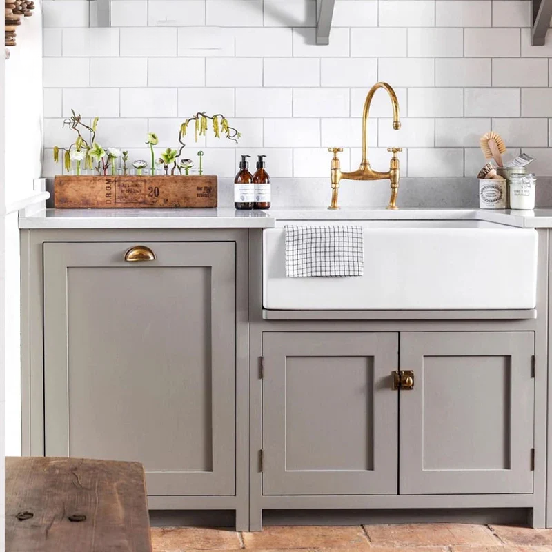 Modern kitchen with gray cabinets, white countertop, and gold faucet.