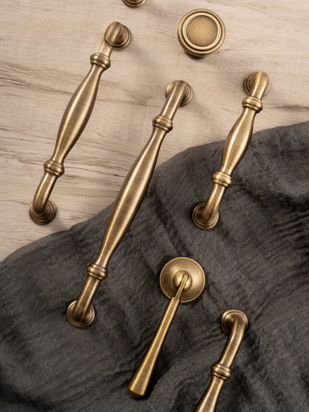 Set of brass cabinet handles on a wooden tray with a neutral background