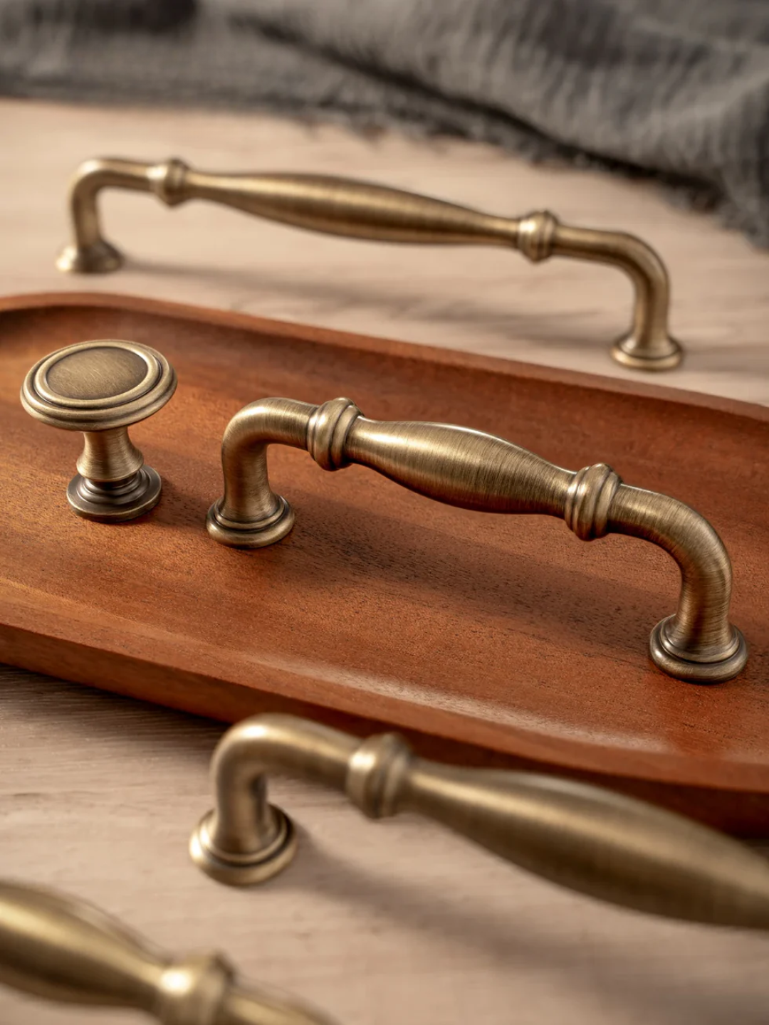 Set of brass cabinet handles on a wooden tray with a neutral background