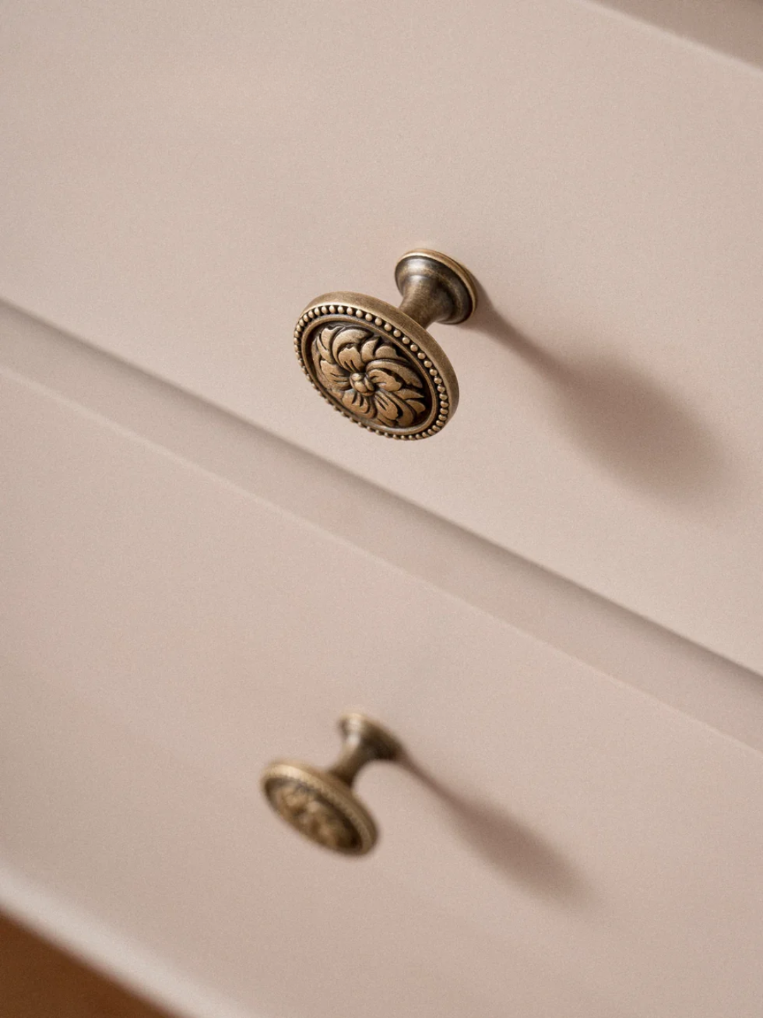 Close-up of a cabinet with decorative brass knobs on a beige background