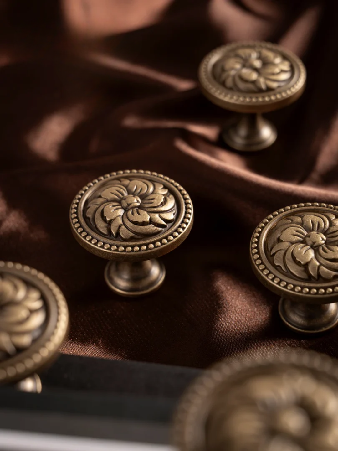 Decorative bronze knobs on a fabric surface with a blurred background