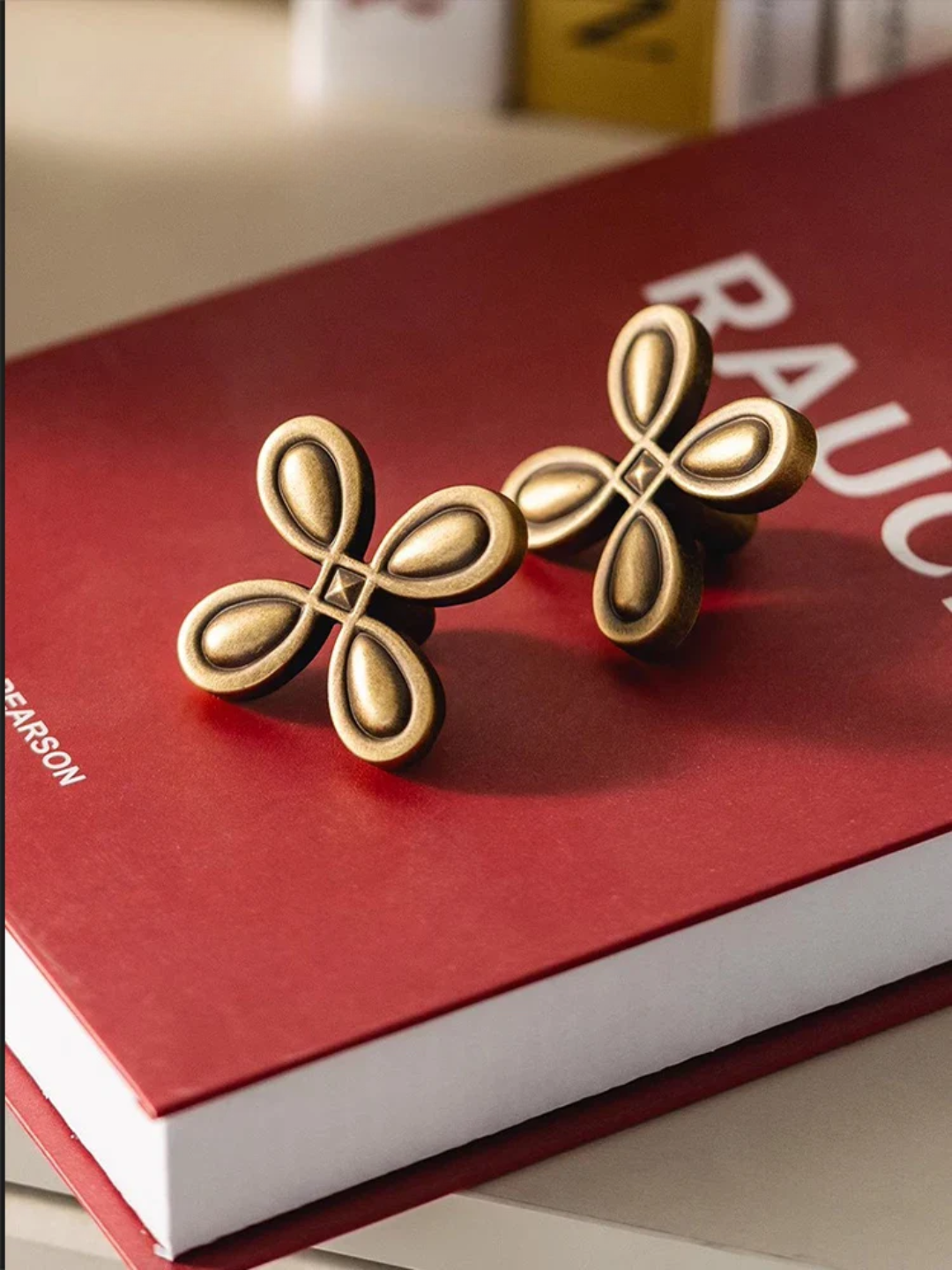 Pair of gold butterfly-shaped earrings on a red book