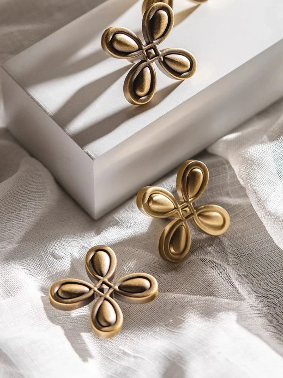 Gold floral earrings on a white fabric background