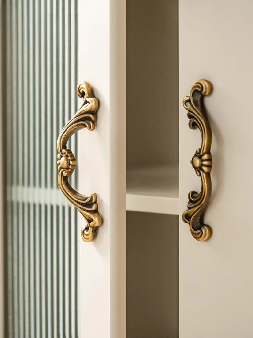 Close-up of ornate gold handles on a door with glass panels.