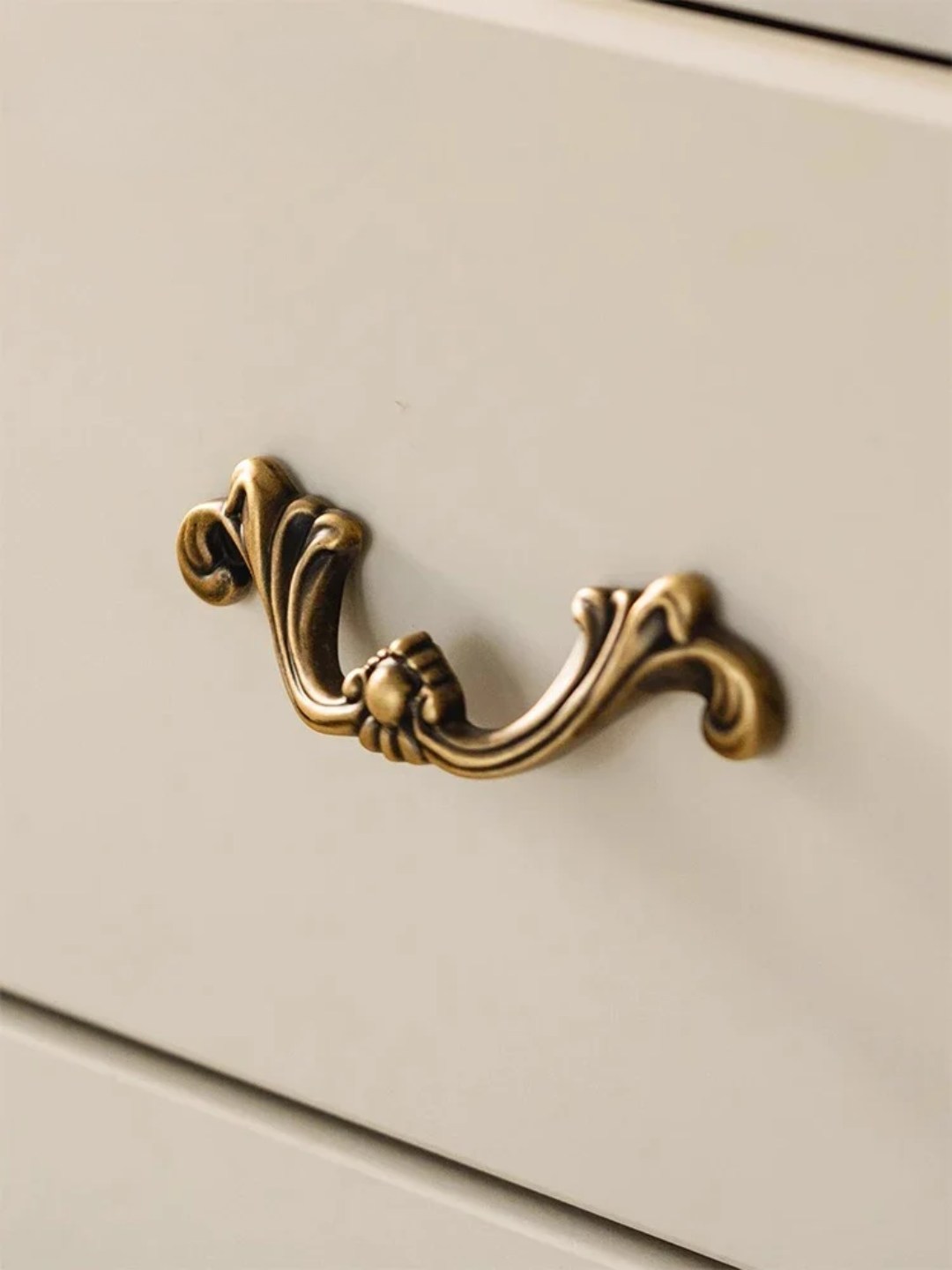 Decorative brass cabinet handle on a beige drawer