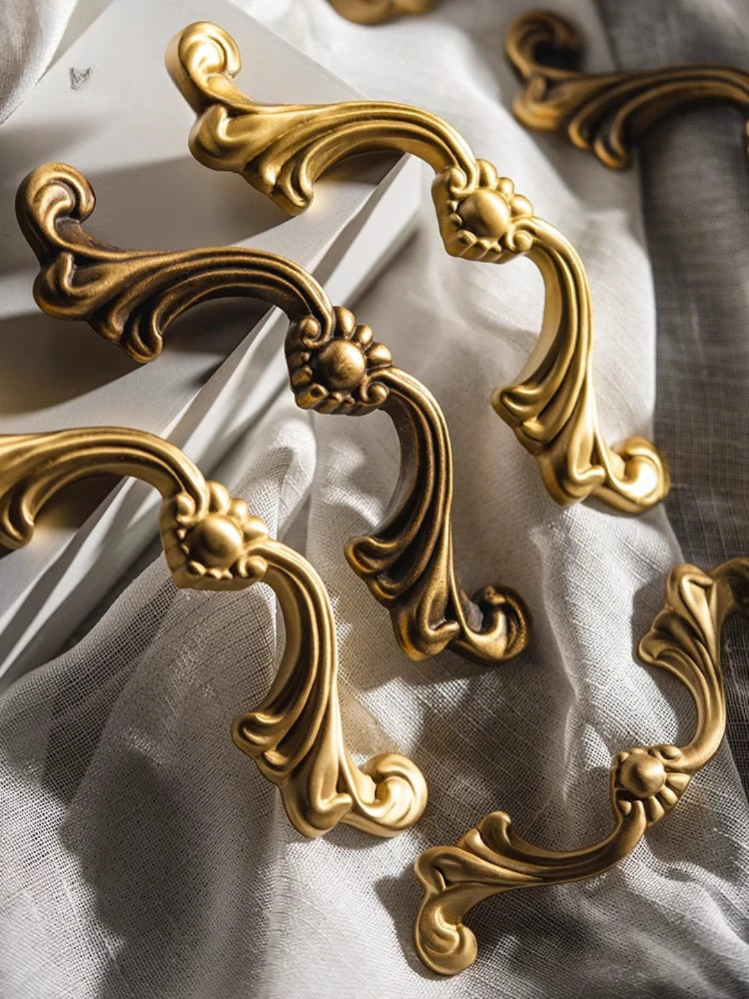 Decorative gold cabinet handles on a light fabric background