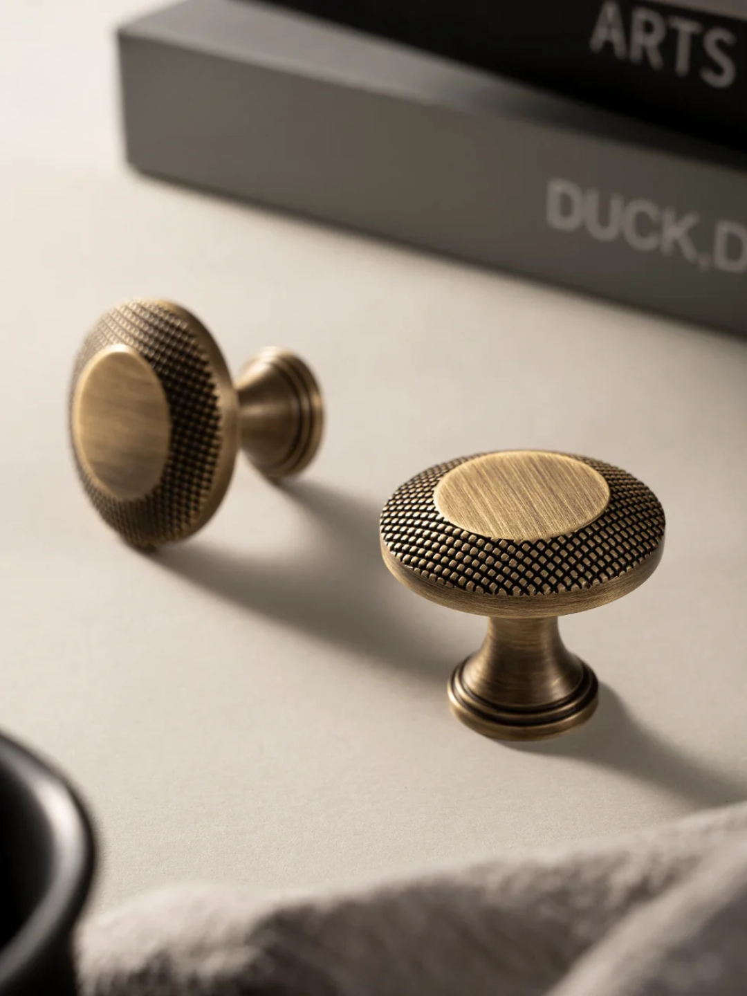 Two brass cabinet knobs on a light surface with a blurred background.