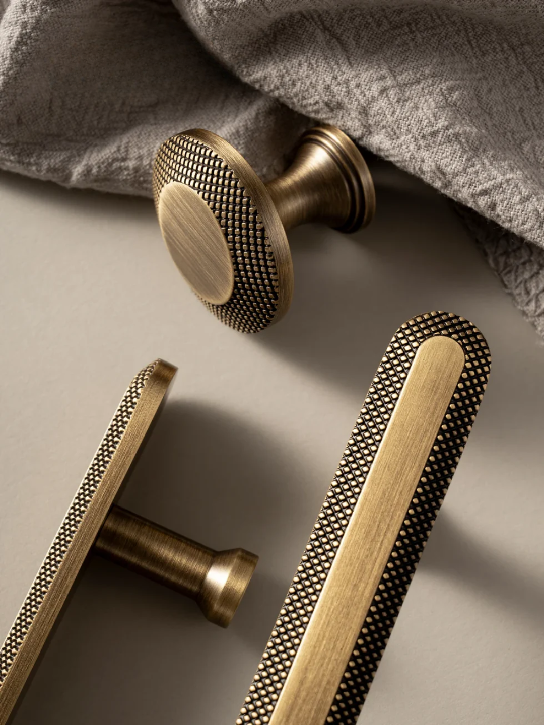 Bronze door handles on a textured surface with a fabric background