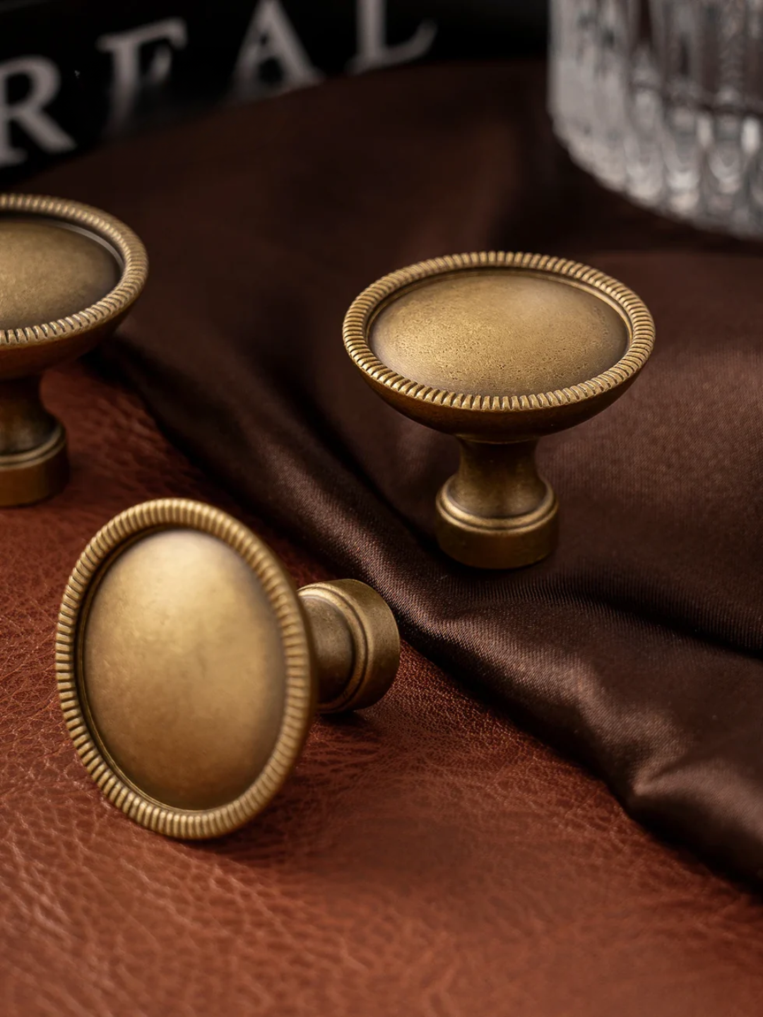 Brass cabinet knobs on a brown fabric background