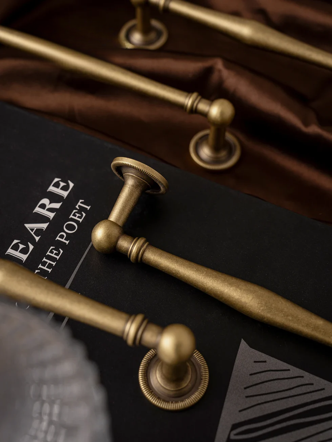 Close-up of brass handles on a book titled 'Shakespeare the Poet'.