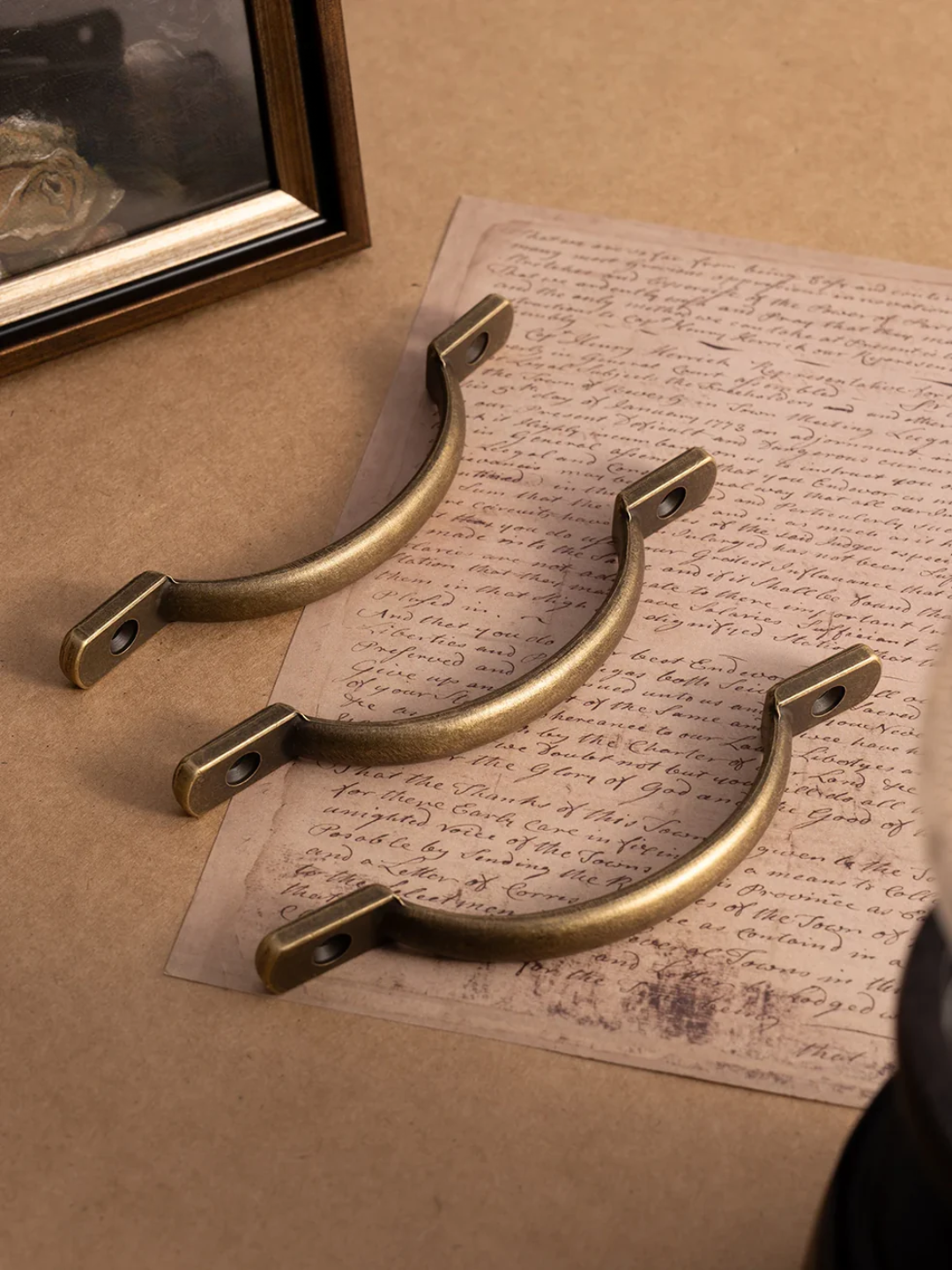 Three brass handles on a textured surface with a piece of paper underneath