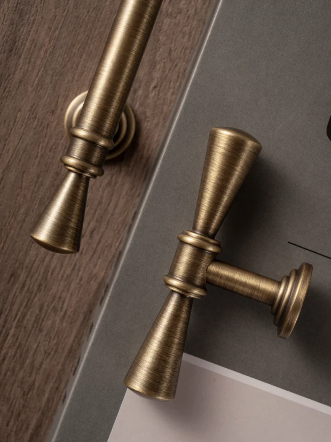 Close-up of two brass curtain rods on a wooden and gray background