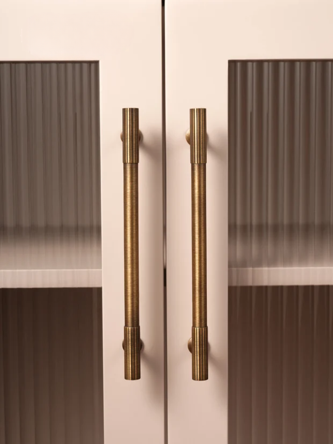 Cabinet doors with bronze handles on a light pink background