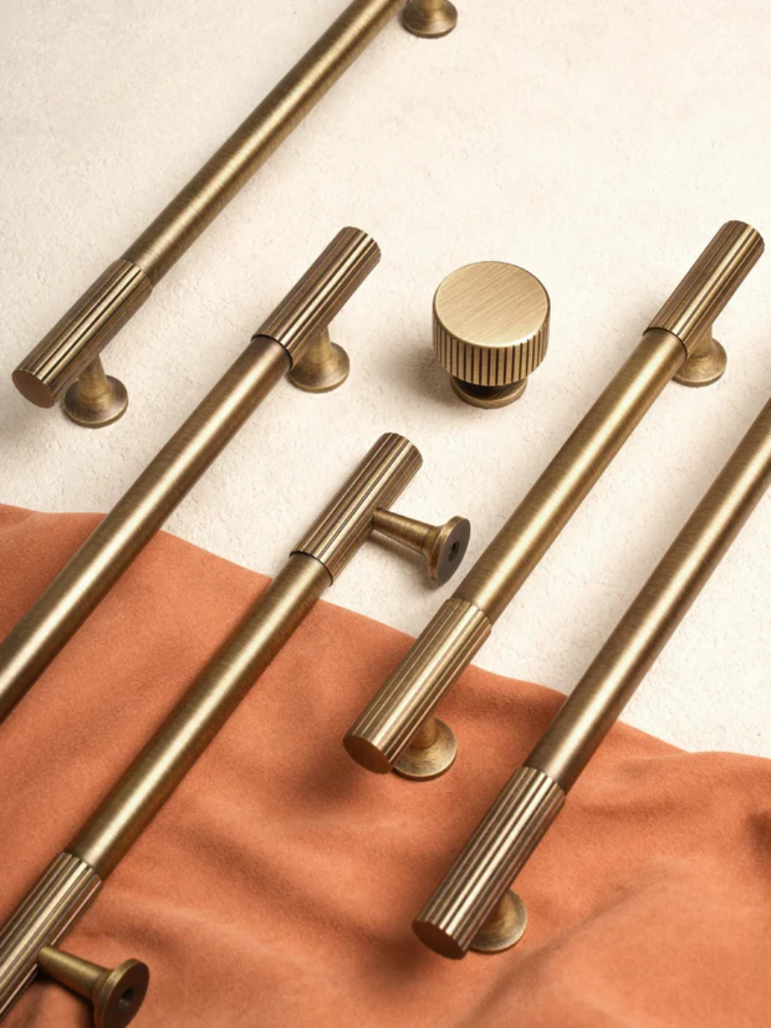 Set of gold cabinet handles and knobs on a neutral background