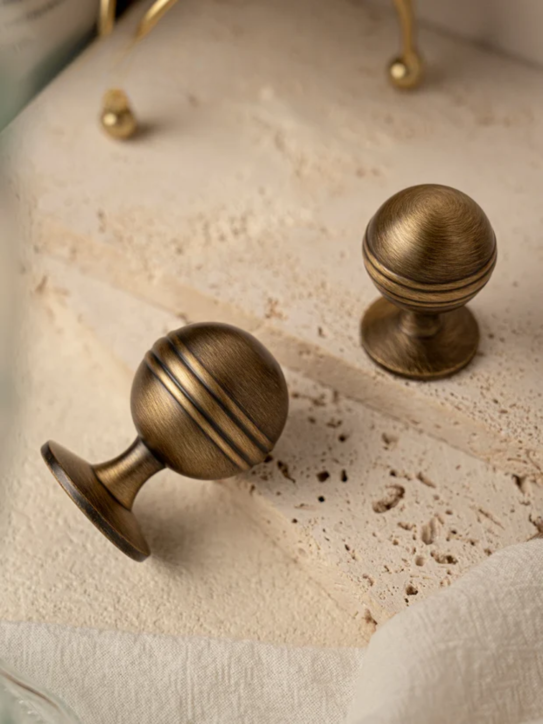 Two bronze cabinet knobs on a textured surface with 'Santaya' branding.
