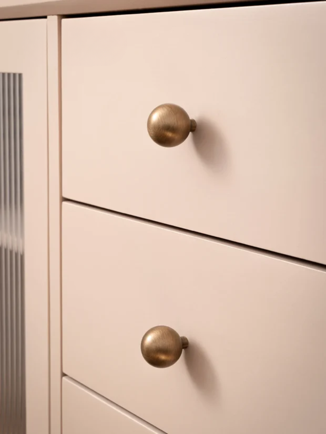 Close-up of a light pink cabinet with gold knobs, featuring the Santaya brand.