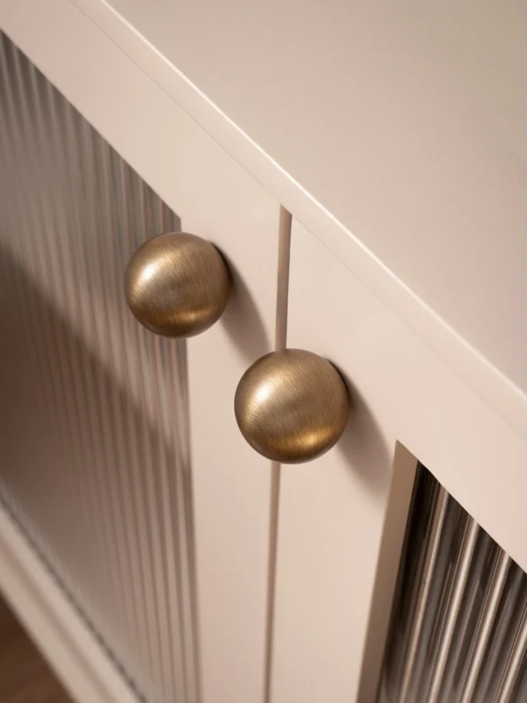 Close-up of a cabinet with gold knobs on a light wood background, featuring the Santaya brand.