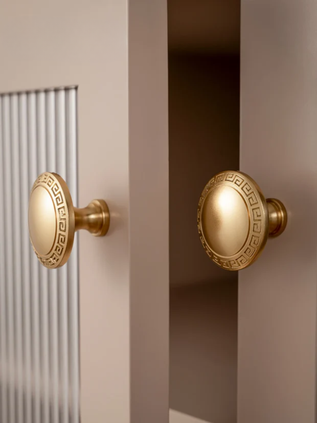 Close-up of gold cabinet knobs on a neutral background