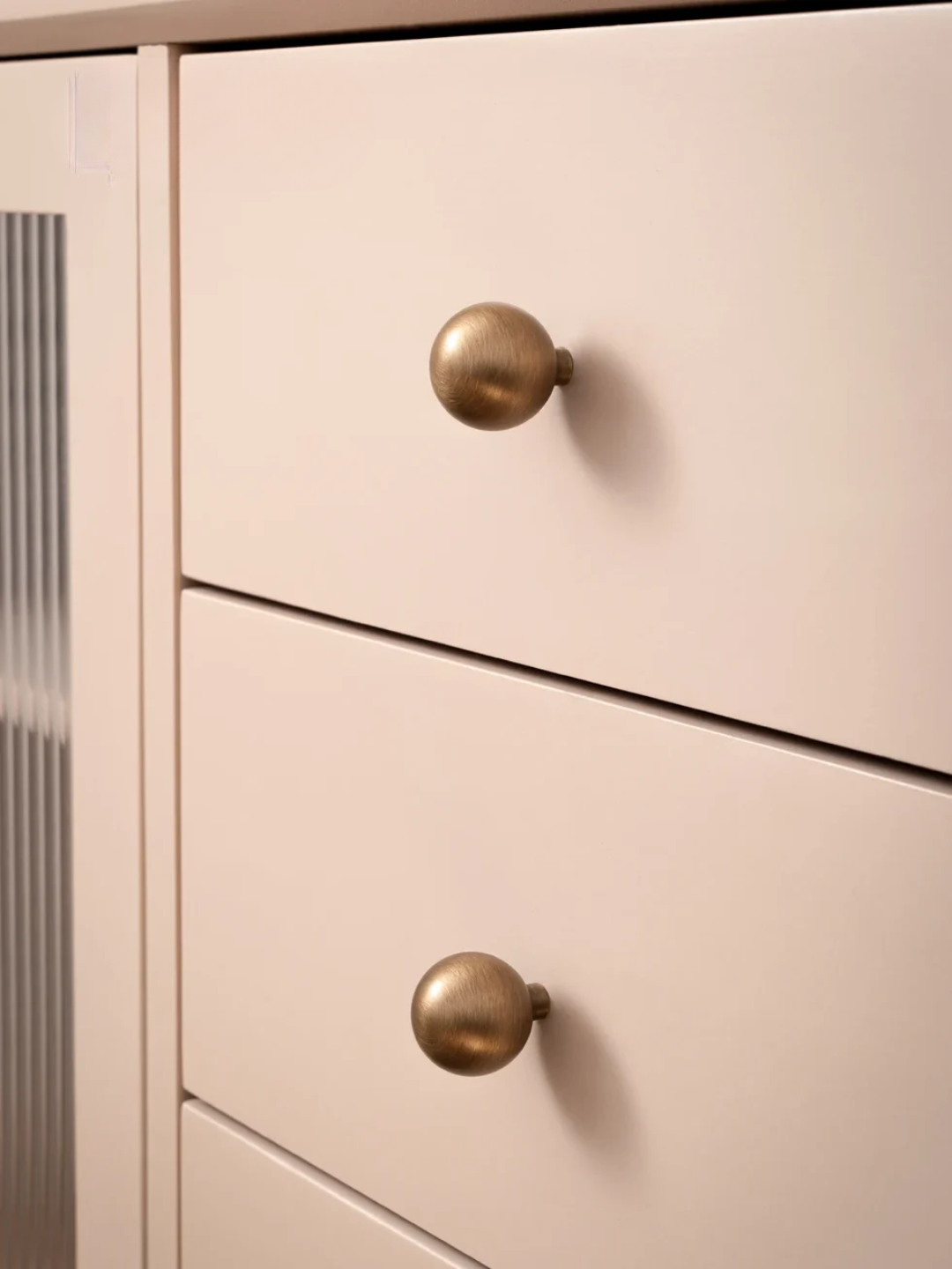Close-up of a light pink cabinet with gold knobs, featuring the Santaya brand.