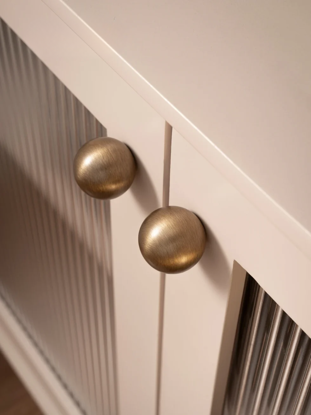 Close-up of a white cabinet with gold knobs