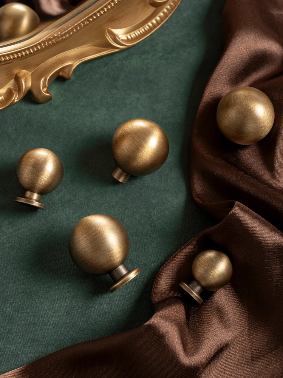 Bronze door knobs on a green surface with brown fabric