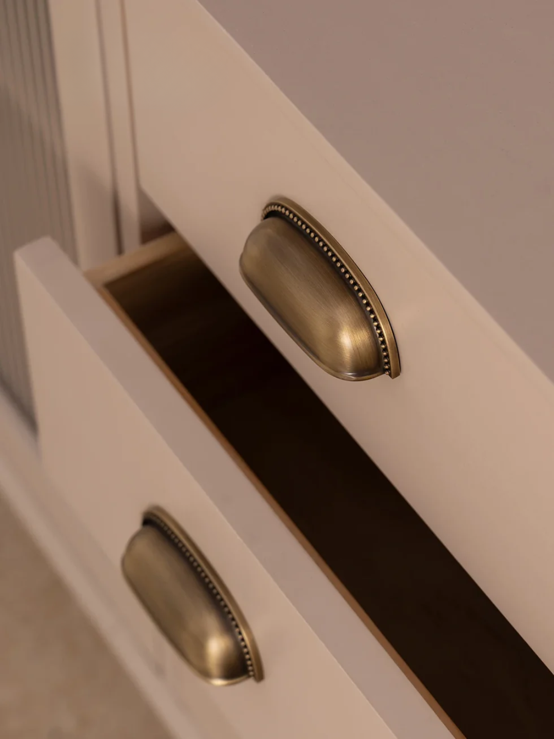 Close-up of a white cabinet with brass handles on a neutral background