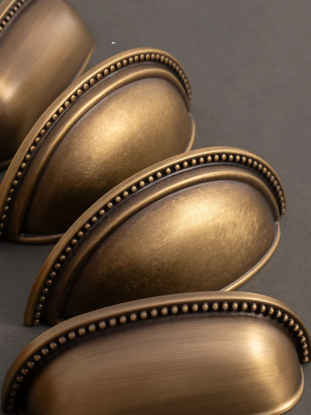 Close-up of bronze cabinet handles on a gray background