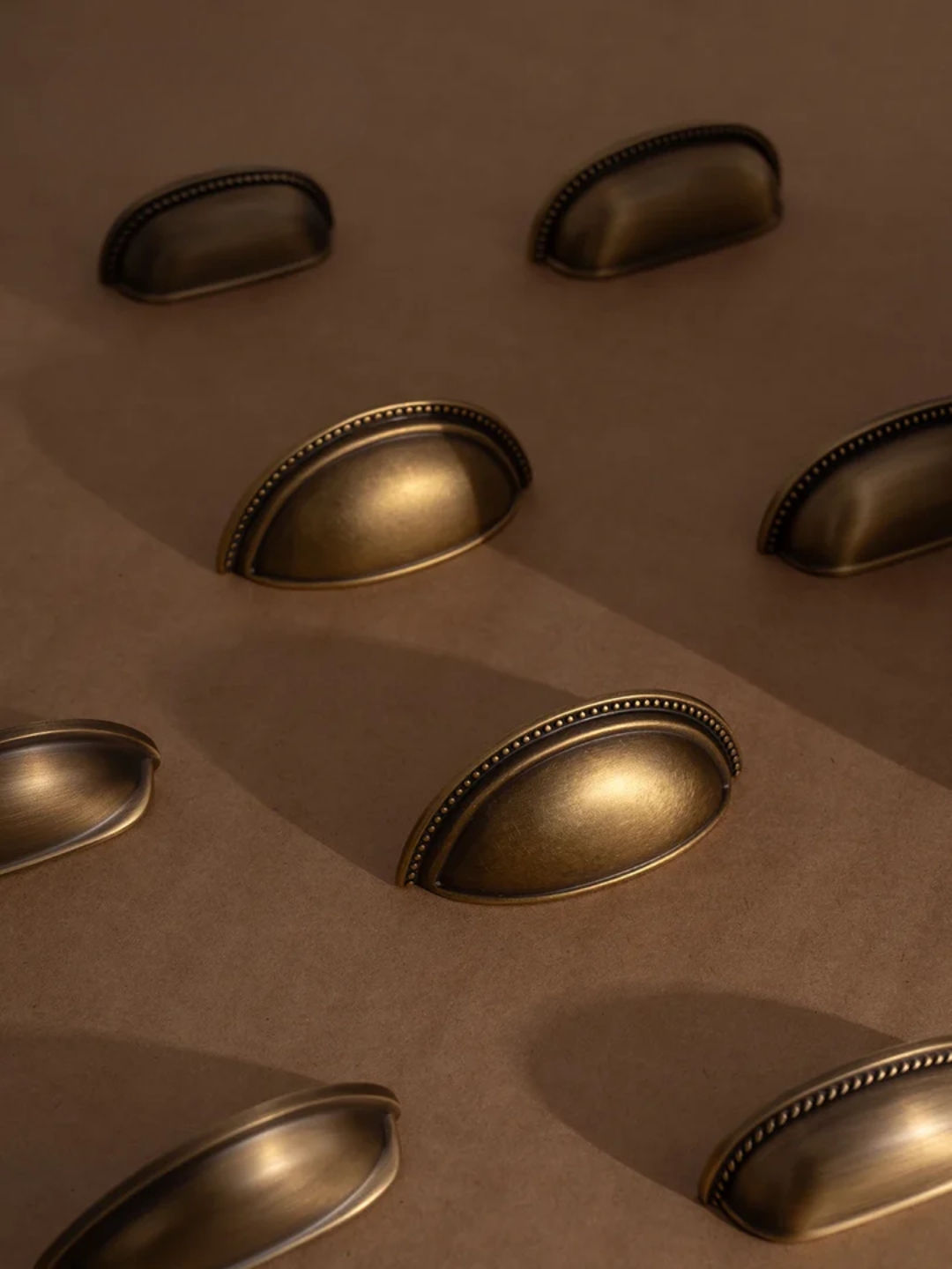 Set of five brass cabinet handles on a beige background