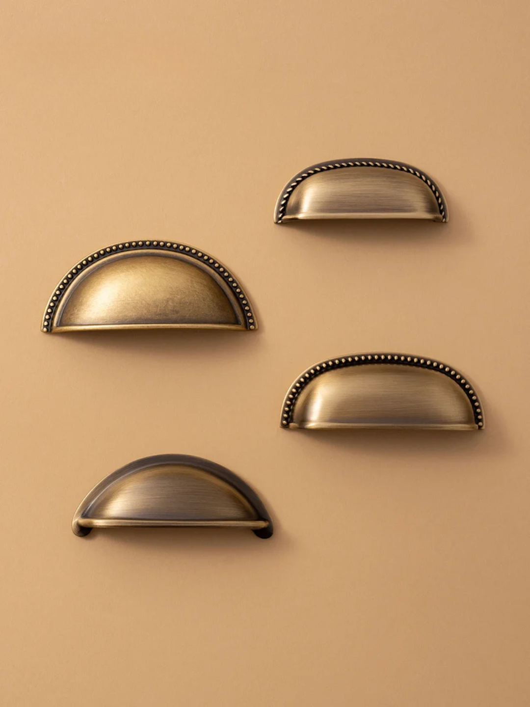 Set of five brass cabinet handles on a beige background