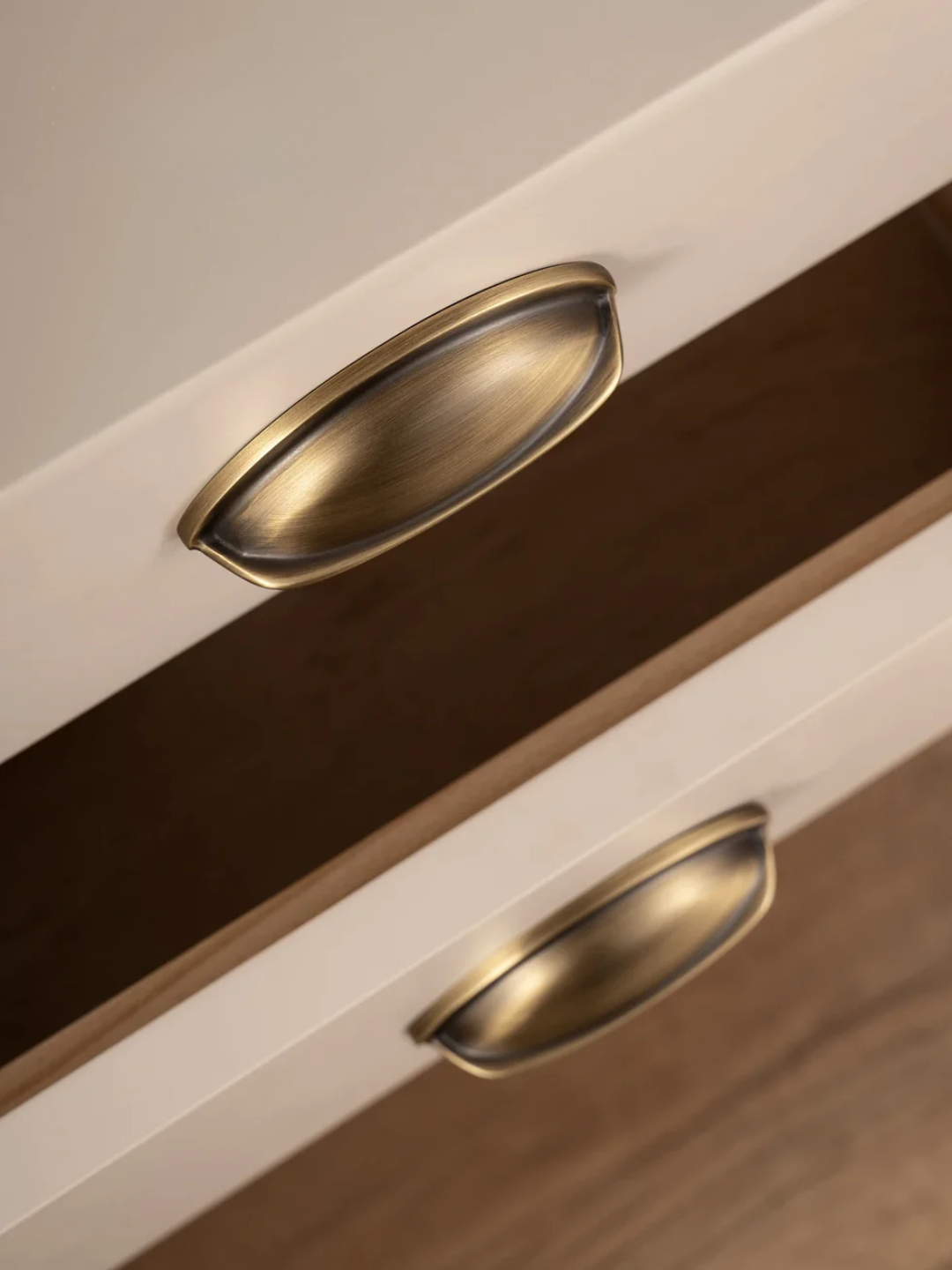 Close-up of a wooden drawer with brass handles on a neutral background