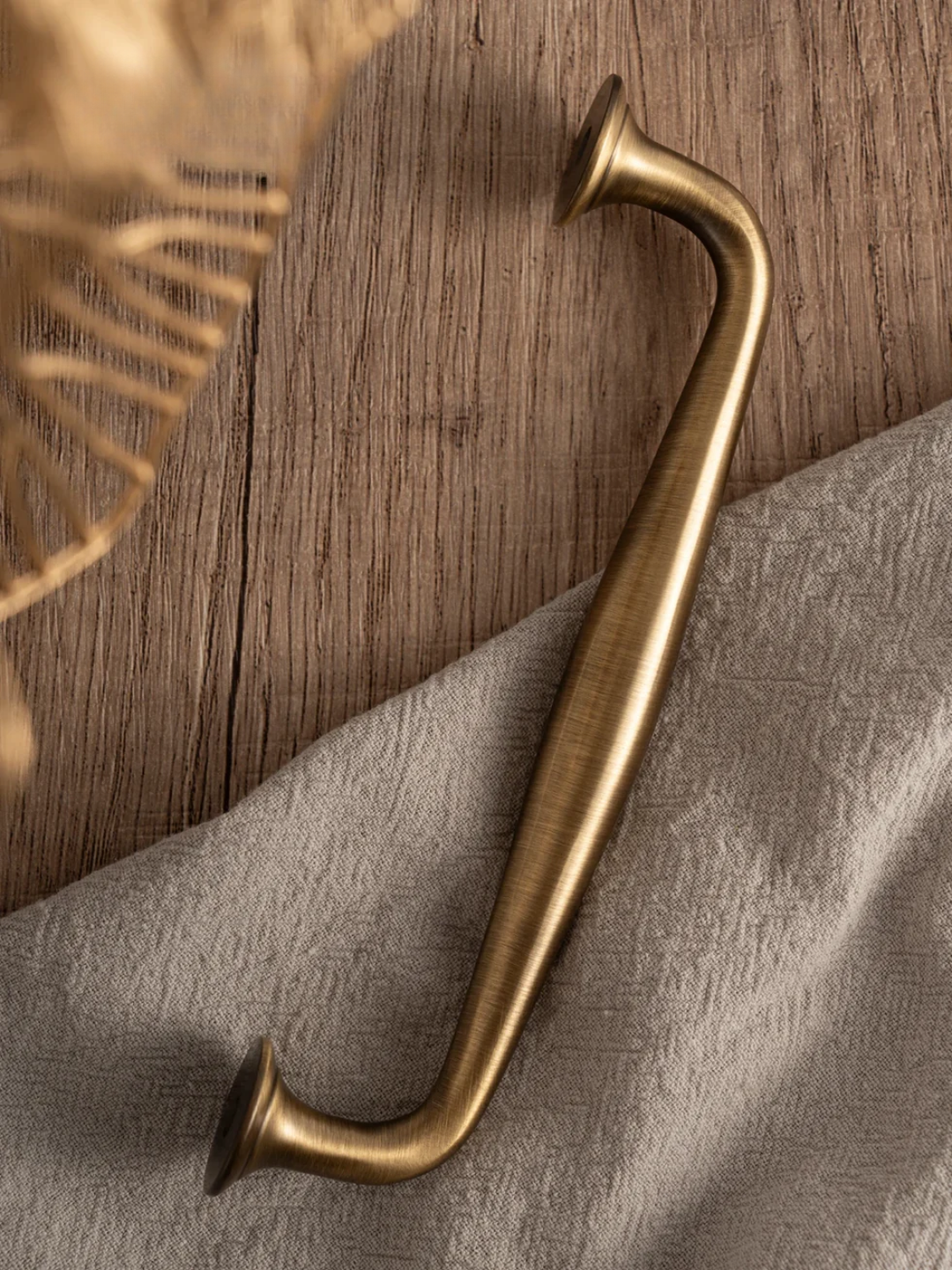 Brass handle on a wooden surface with a textured fabric background