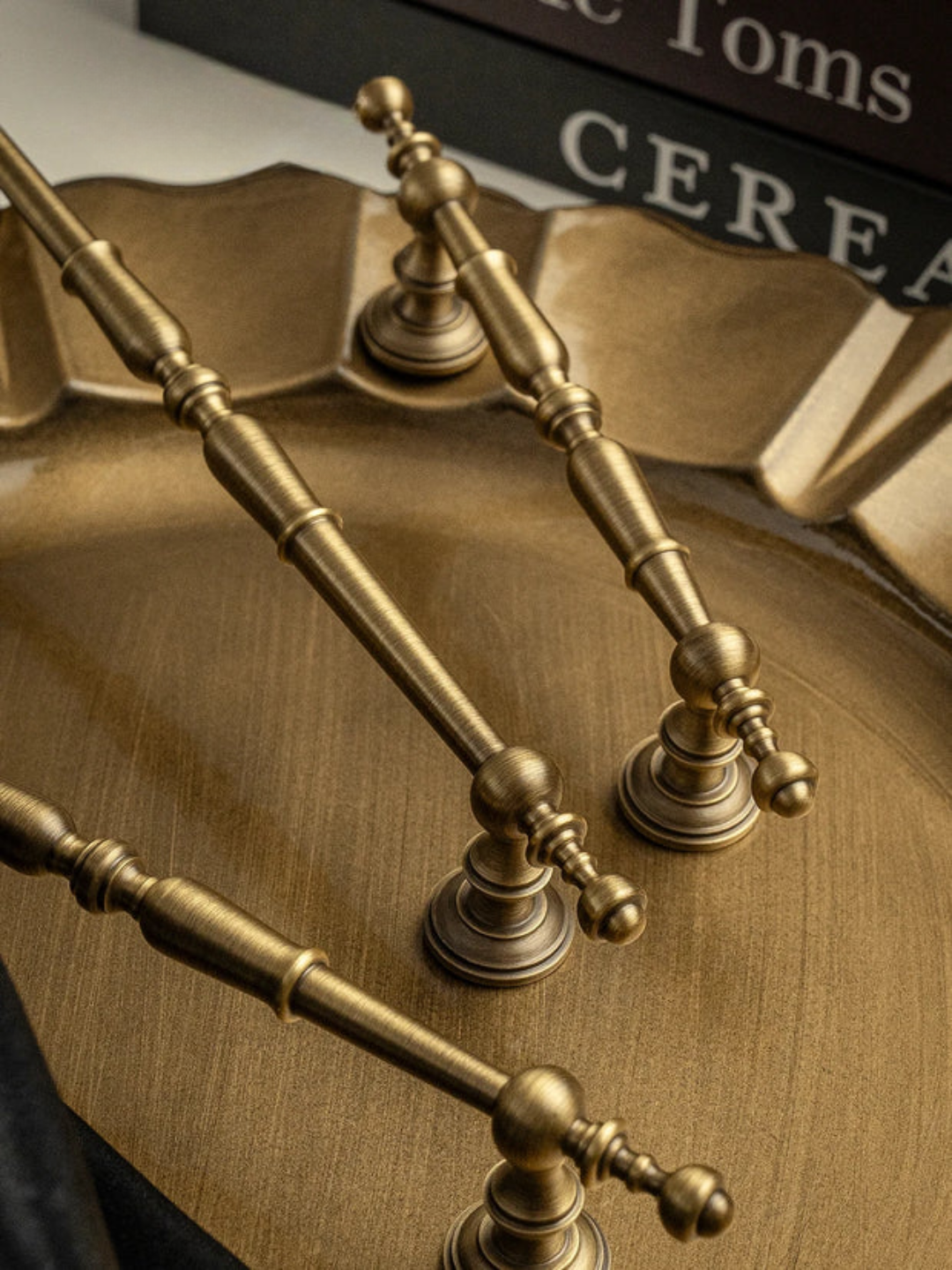 Close-up of ornate brass handles on a wooden surface with 'Toms' branding in the background.