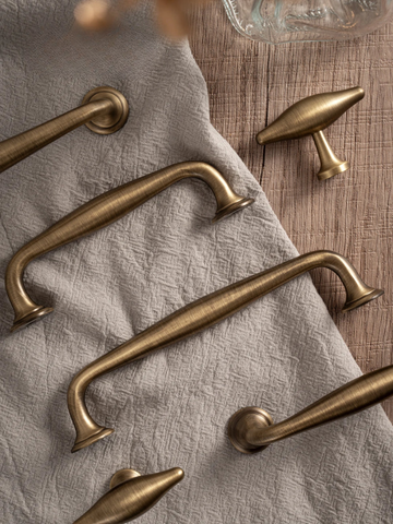 Set of brass cabinet handles on a textured fabric surface
