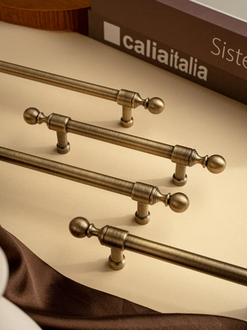 Set of brass cabinet handles on a brown surface.