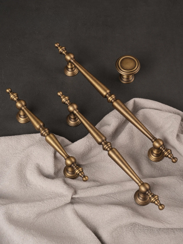Set of vintage-style brass cabinet handles on a dark background