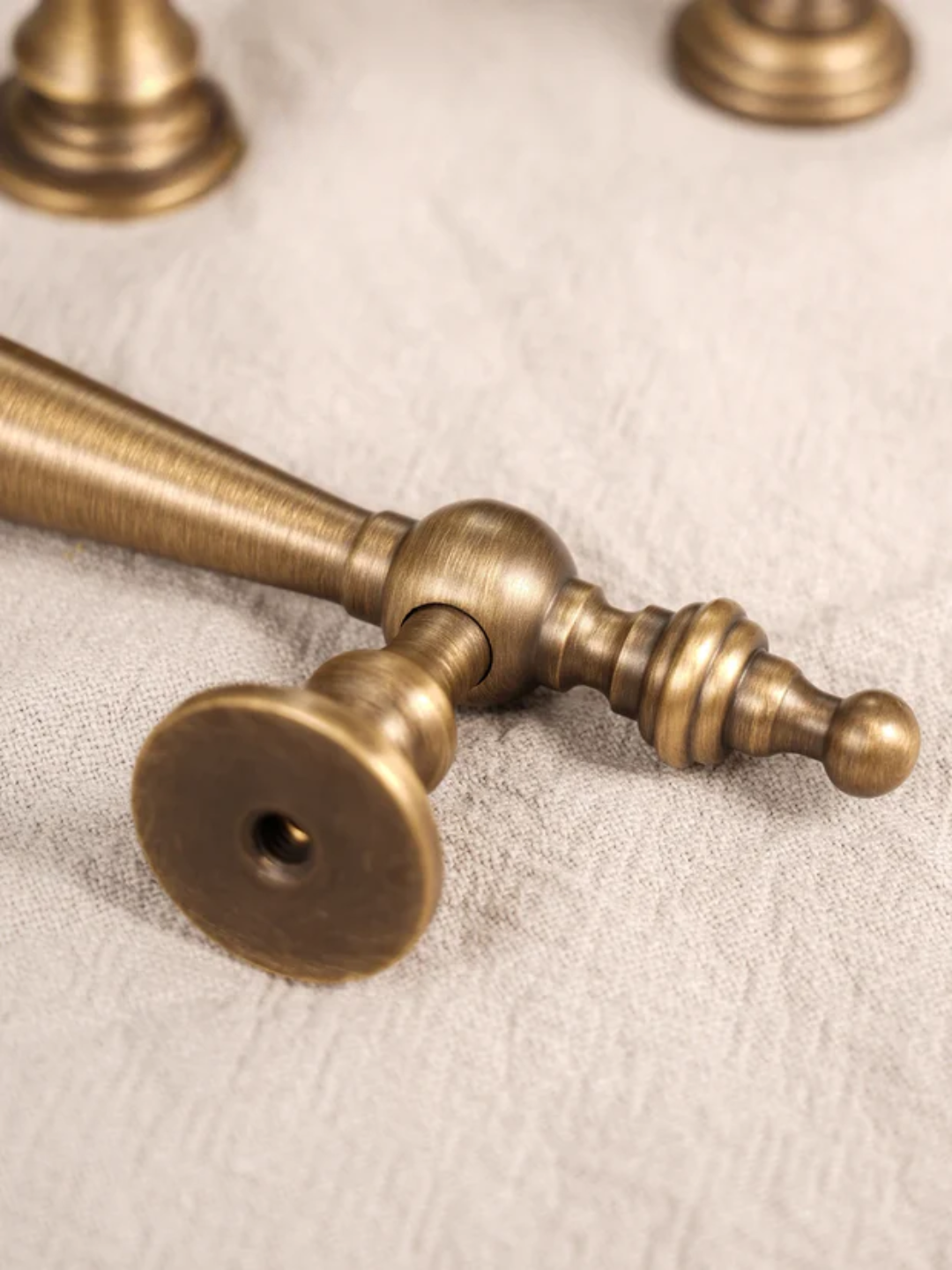 Close-up of a brass curtain rod on a textured beige background