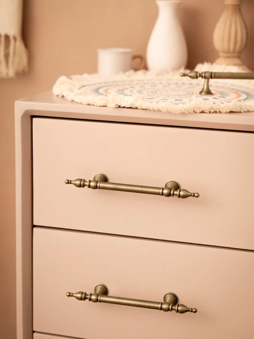 Beige dresser with brass handles on a beige background