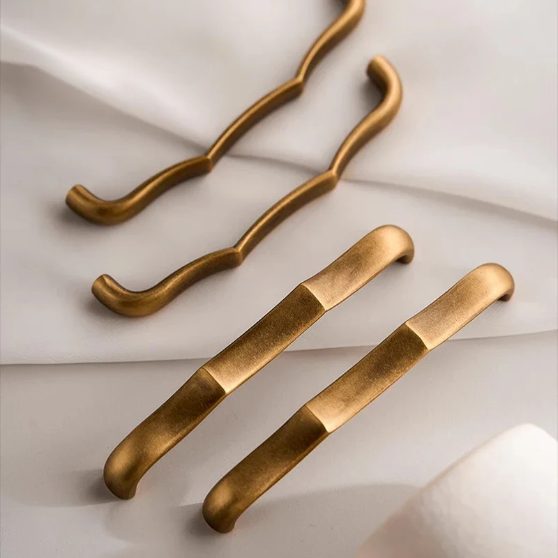 Brass cabinet handles on a soft white background.