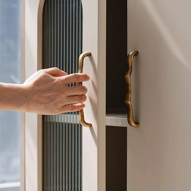 Hand opening a cabinet door with brass handle
